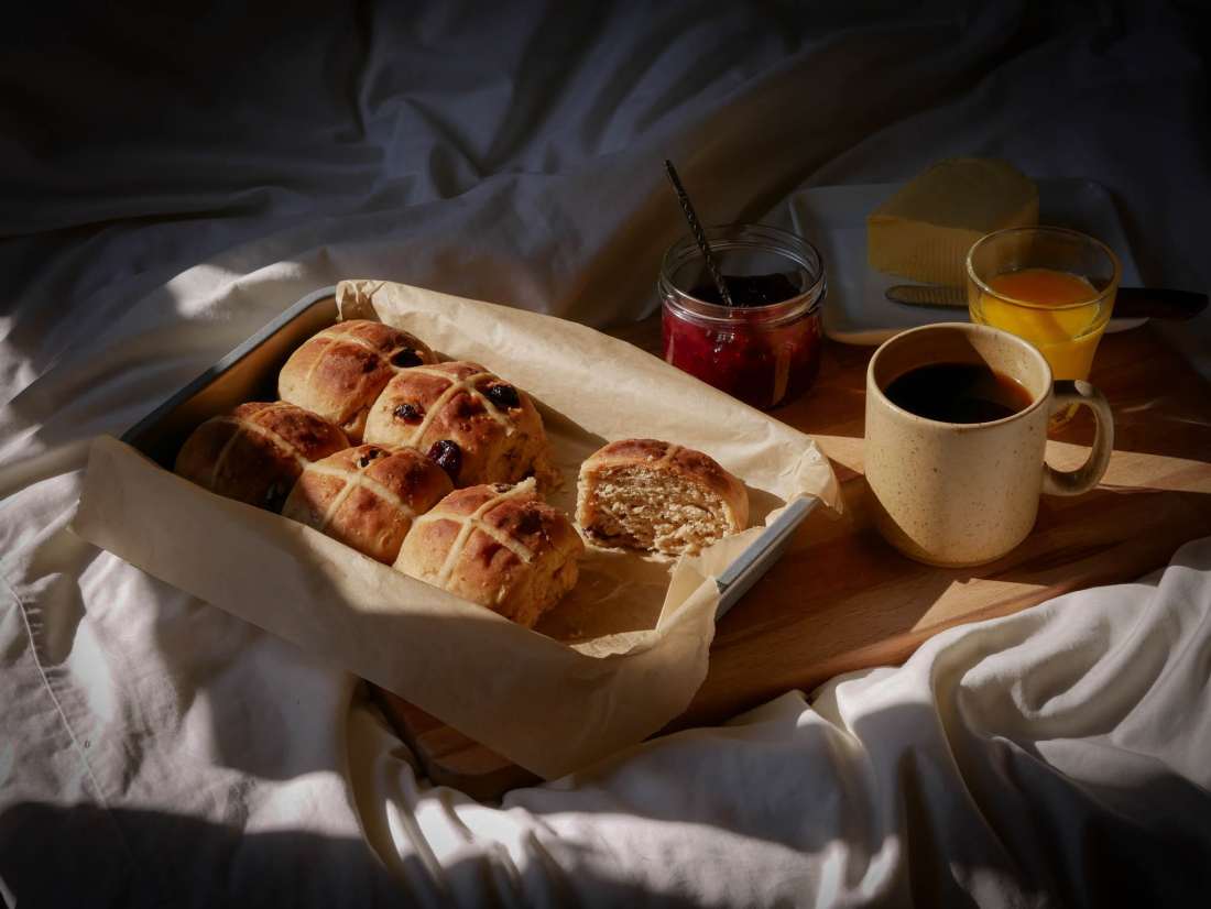 Petit-déjeuner au lit avec des hot cross buns, du beurre, de la confiture, du café